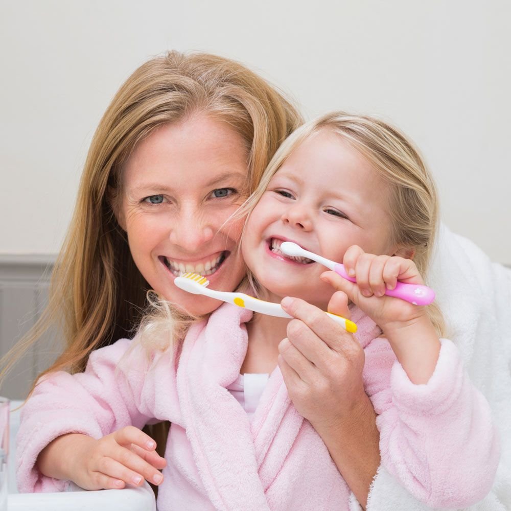 Smiling mom and daughter brushing teeth