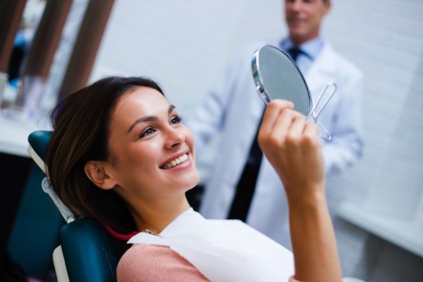 Happy patient looking at smile in the mirror