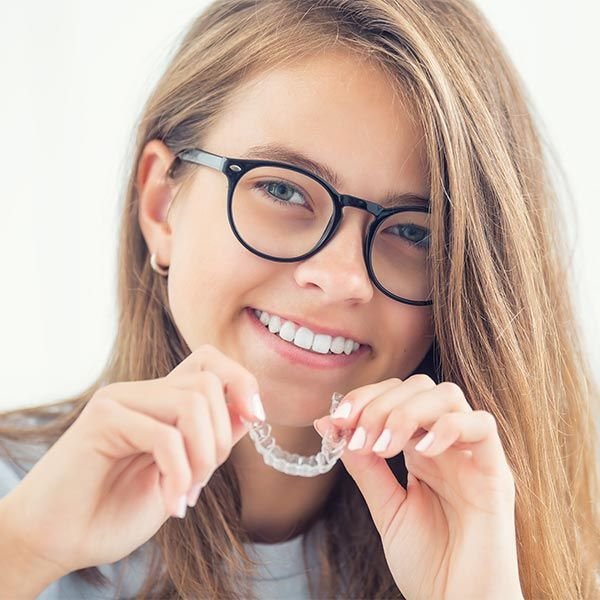 A woman holding an Invisalign aligner